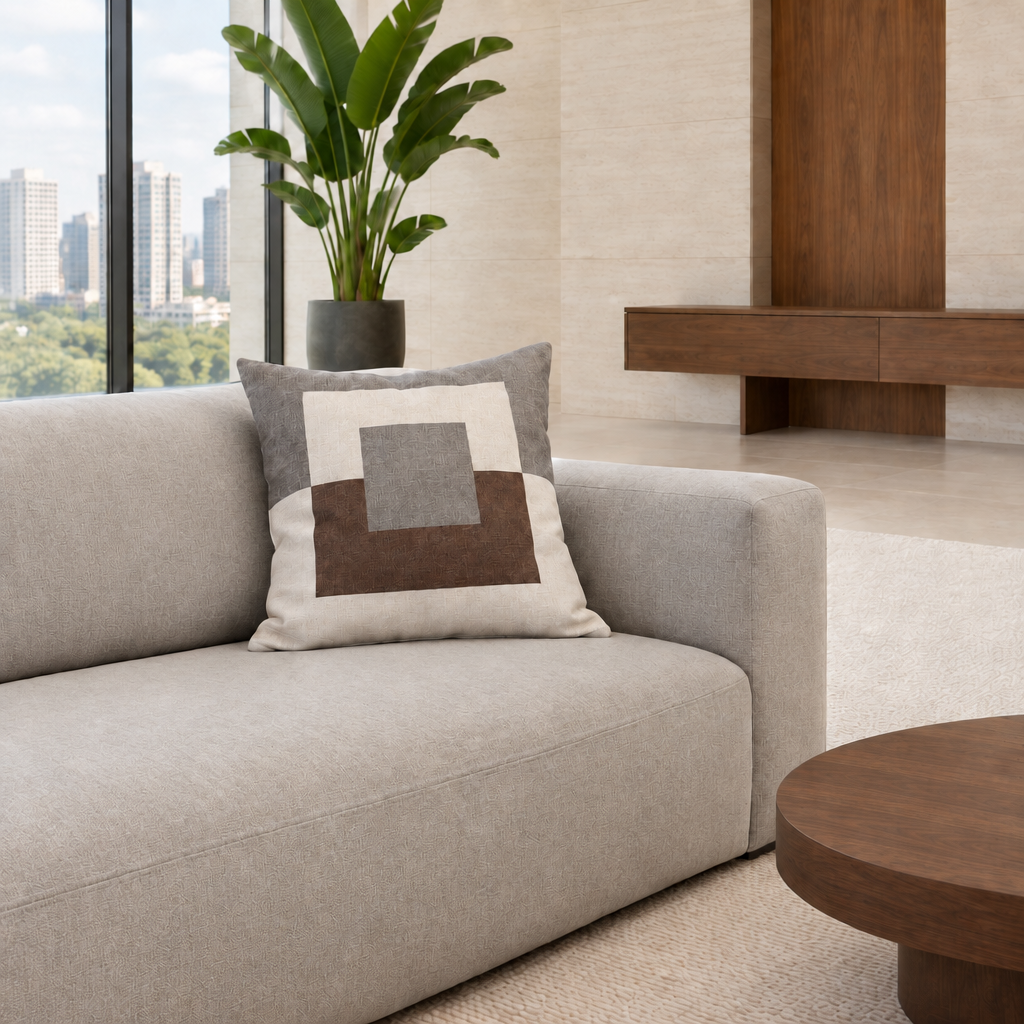 Cojín geométrico gris de 50 x 50 cm con textura natural en un living luminoso con mesa redonda de nogal