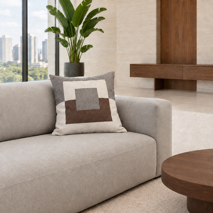 Cojín geométrico gris de 50 x 50 cm con textura natural en un living luminoso con mesa redonda de nogal