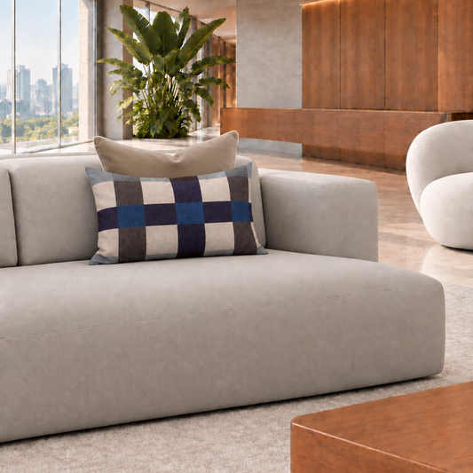Cojín rectangular de cuadros azul de 60 x 40 cm con cojín café detrás en un living contemporáneo luminoso