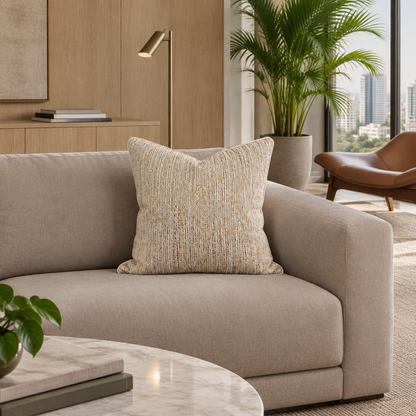 Cojín Yambo Gold II de trama vertical sobre sofá moderno en un departamento luminoso con madera y mármol